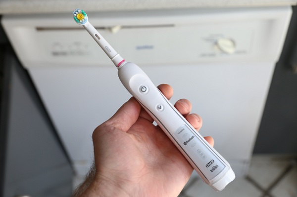 A Woman Holding A Smart Electric Toothbrush Tool Having Sensor In It. 