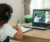 A little girl is learning online with the help of laptop and headphone besides, she has notebook to take notes and pen stand near to her.